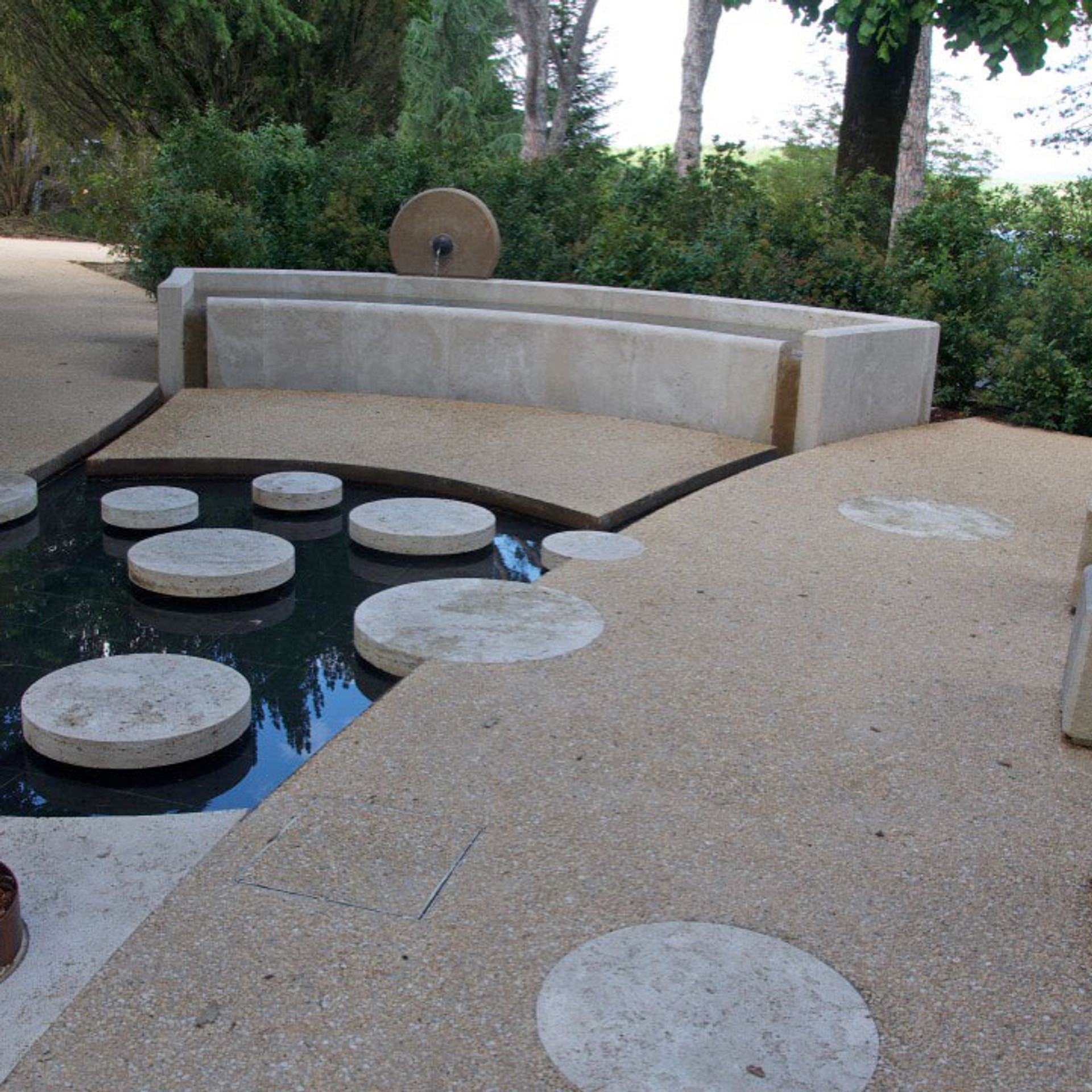 Curved bench beside reflecting pool with stepping stones